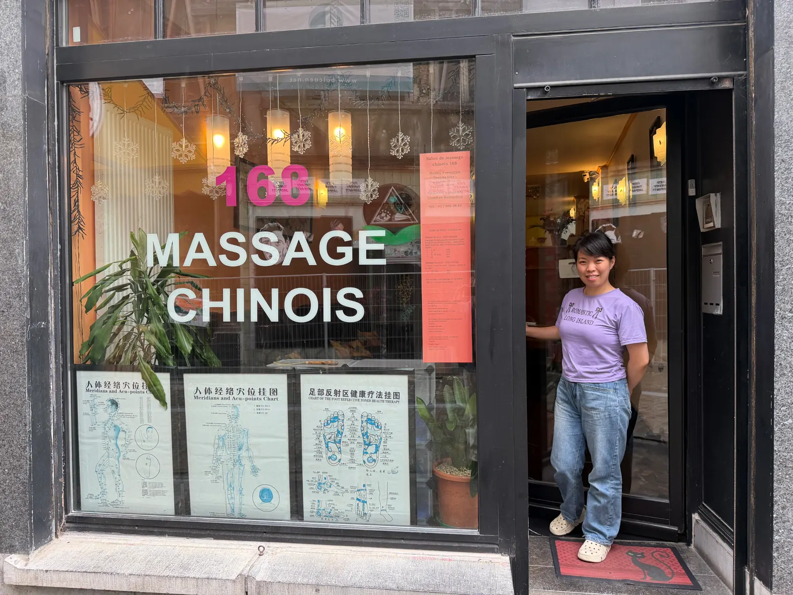 HaiHong souriante devant l'entrée du centre Massage Chinois 168 à Bruxelles